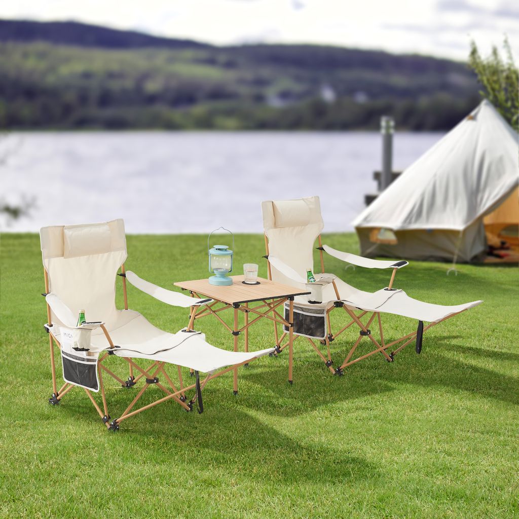 Camping scene with chairs, table, and tent by a lake.