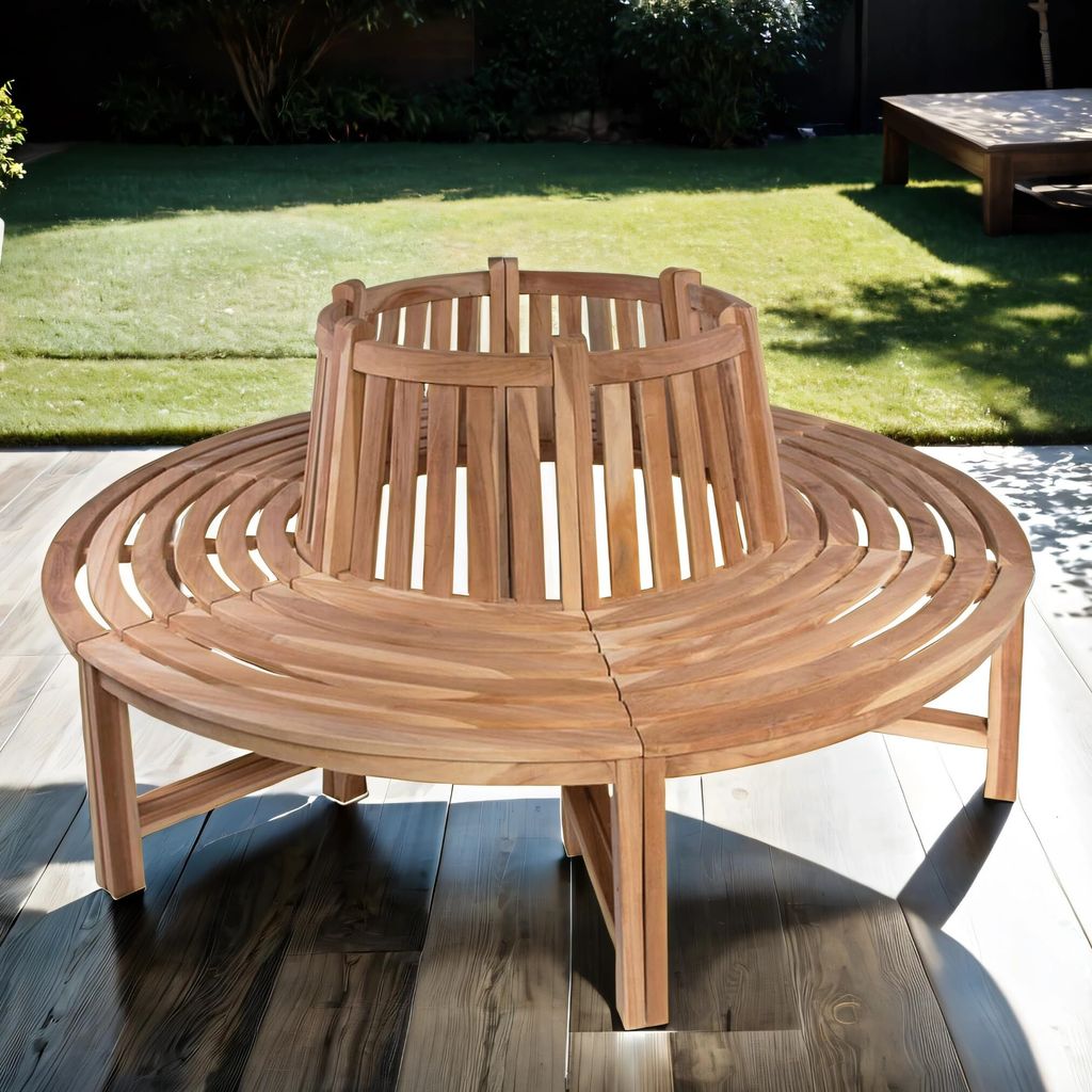 A circular wooden bench is placed on a wooden deck in a garden setting, with a lawn and trees in the background.