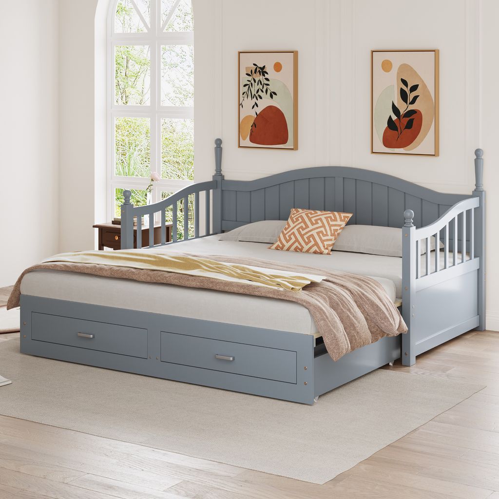 A gray daybed with storage drawers is shown in a room with two abstract art pieces on the wall and a large window in the background.