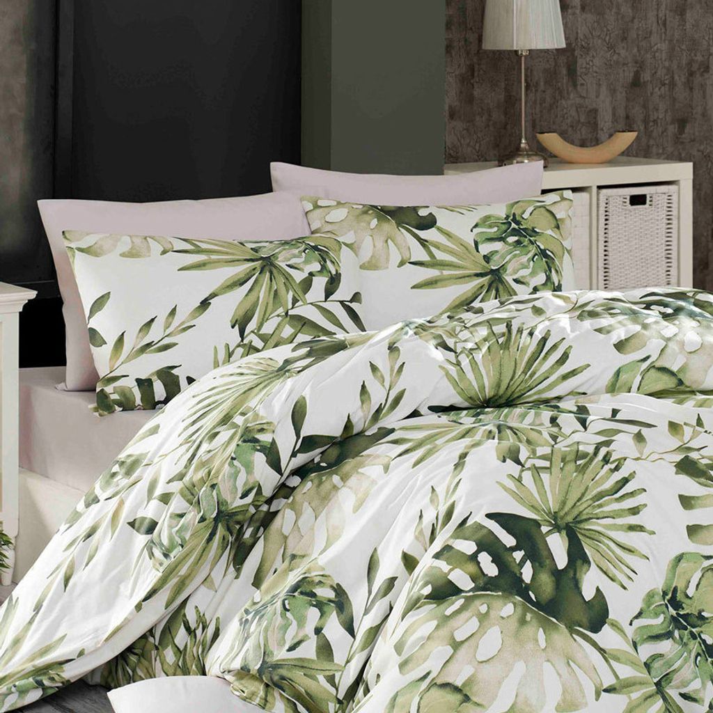 A close-up view of a bed with bedding featuring a green leaf pattern.
