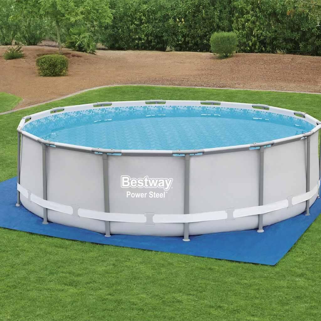 An above-ground swimming pool filled with water, set up on a blue mat on a grassy lawn.