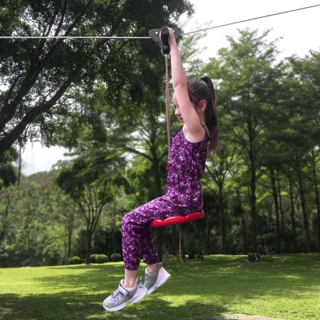 A young girl is using a zipline in a park.