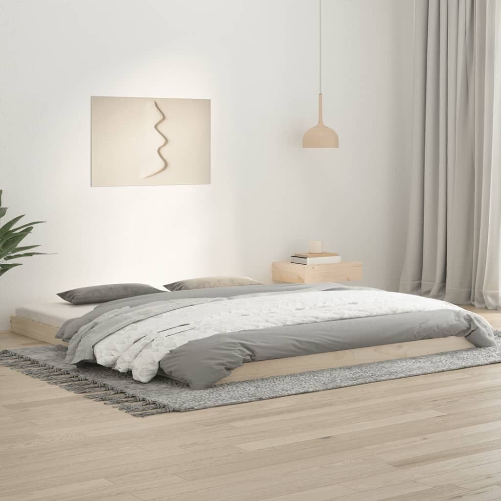 A minimalist bedroom with a wooden platform bed, grey bedding, and a simple wall art.