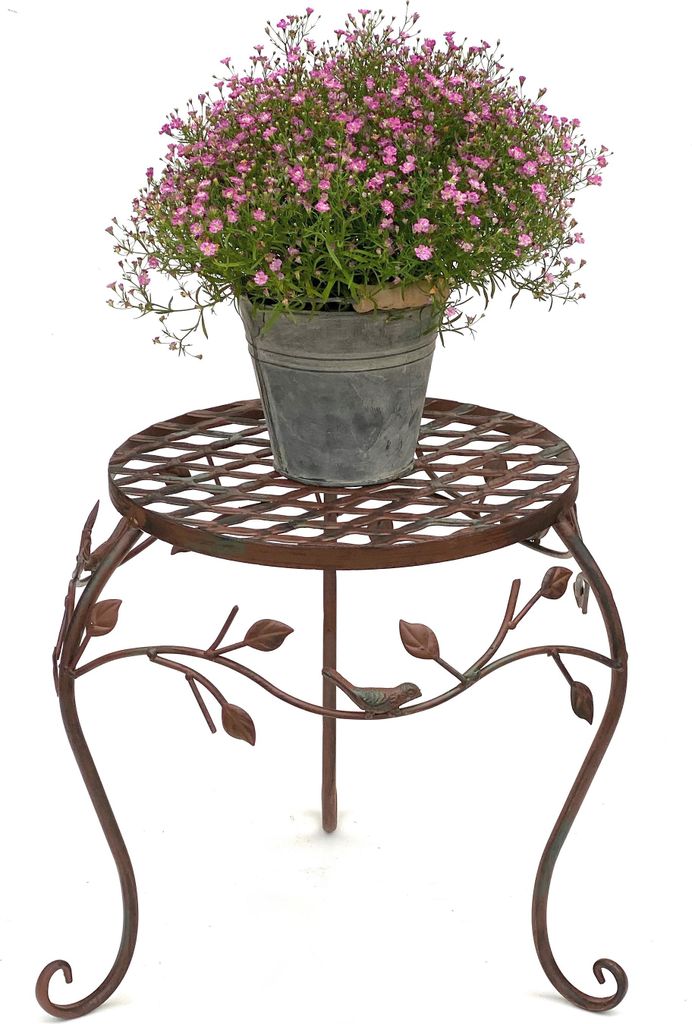 A potted plant with pink flowers sits on a decorative metal plant stand.
