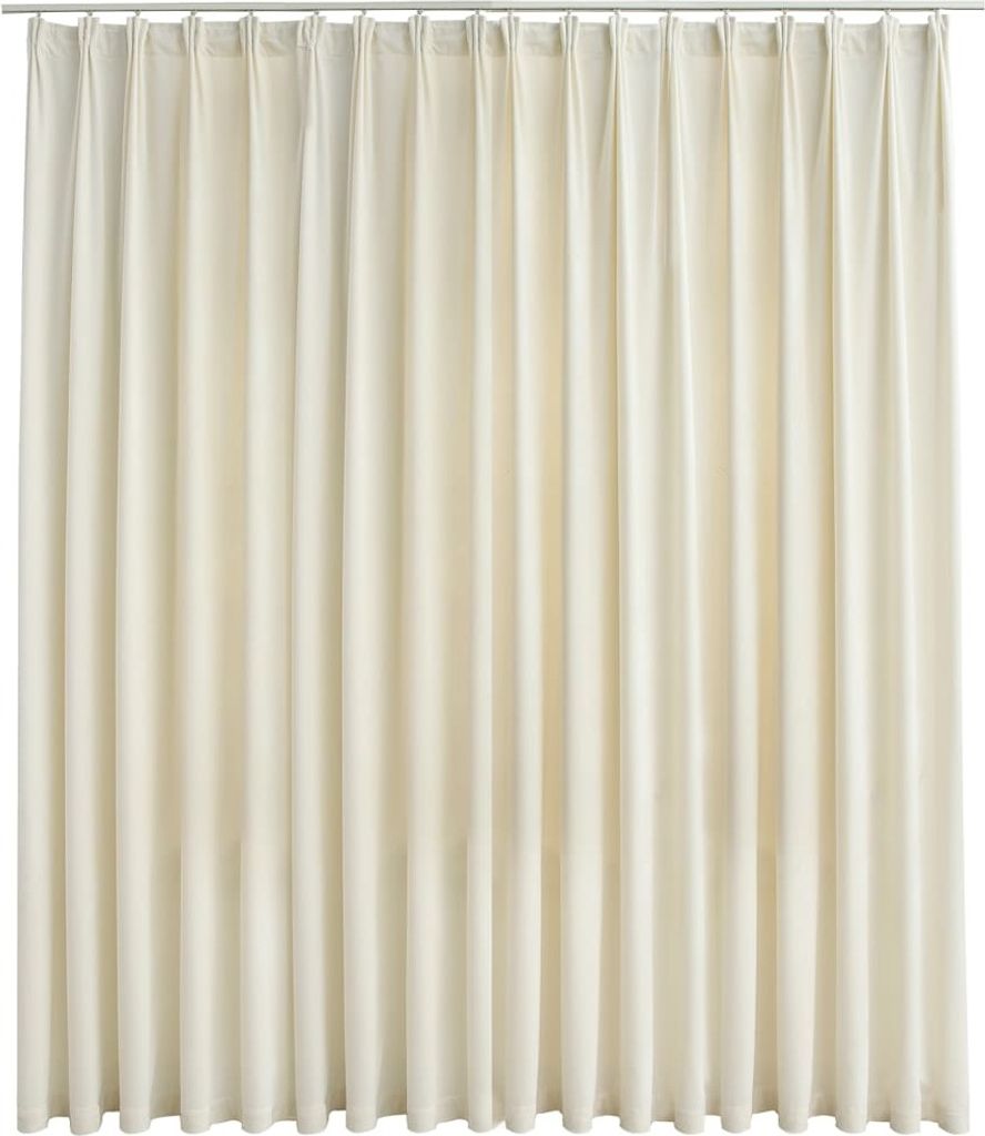 A full-frame shot of a cream-colored velvet curtain hanging from a rod.