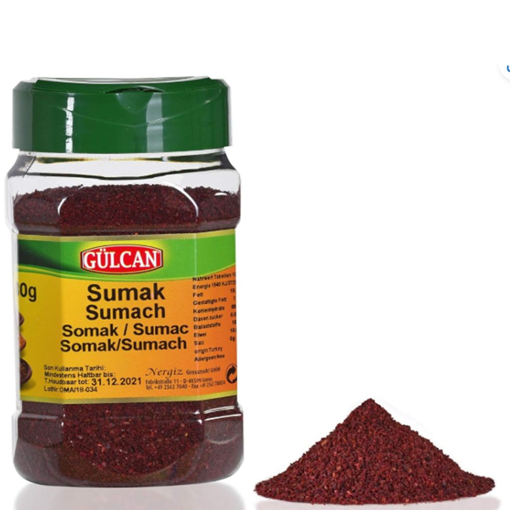 A bottle of Gülcan Sumak spice and a pile of the spice next to it, on a white background.