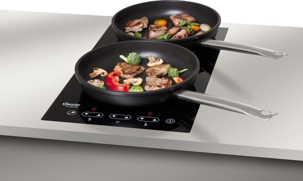 Two frying pans with food cooking on an induction cooktop.