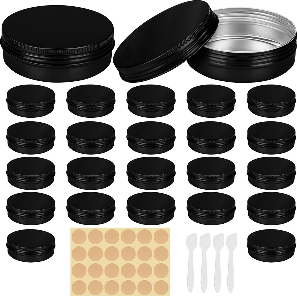 A collection of black aluminum tins with silver interiors and lids, arranged in rows, with a sheet of round stickers and four small white spatulas at the bottom.