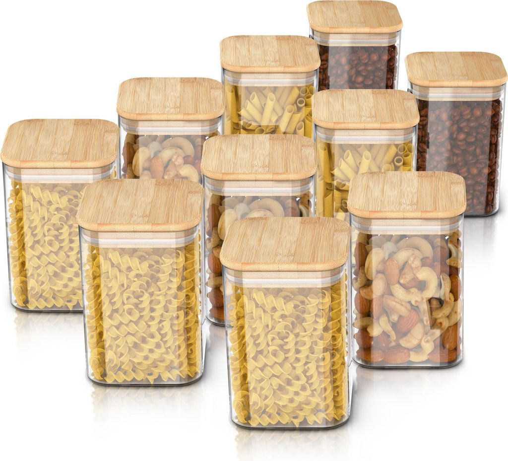 A collection of glass storage jars with bamboo lids, filled with various types of pasta and nuts.