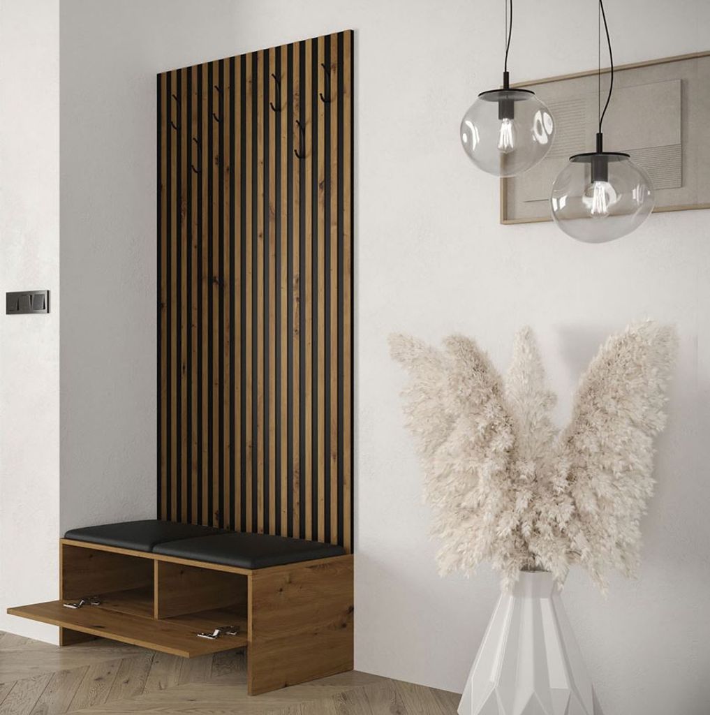 A modern entryway with a wooden slatted panel, a bench with storage, and decorative pampas grass in a vase.