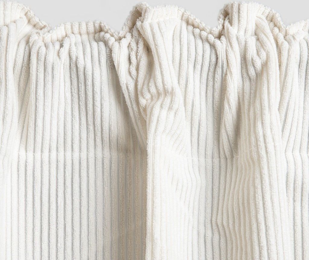 Close-up of a beige corduroy curtain with a ruffled top.