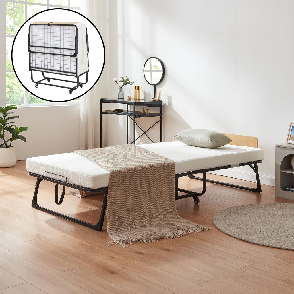 A folding bed is set up in a room with a wooden floor and a window.