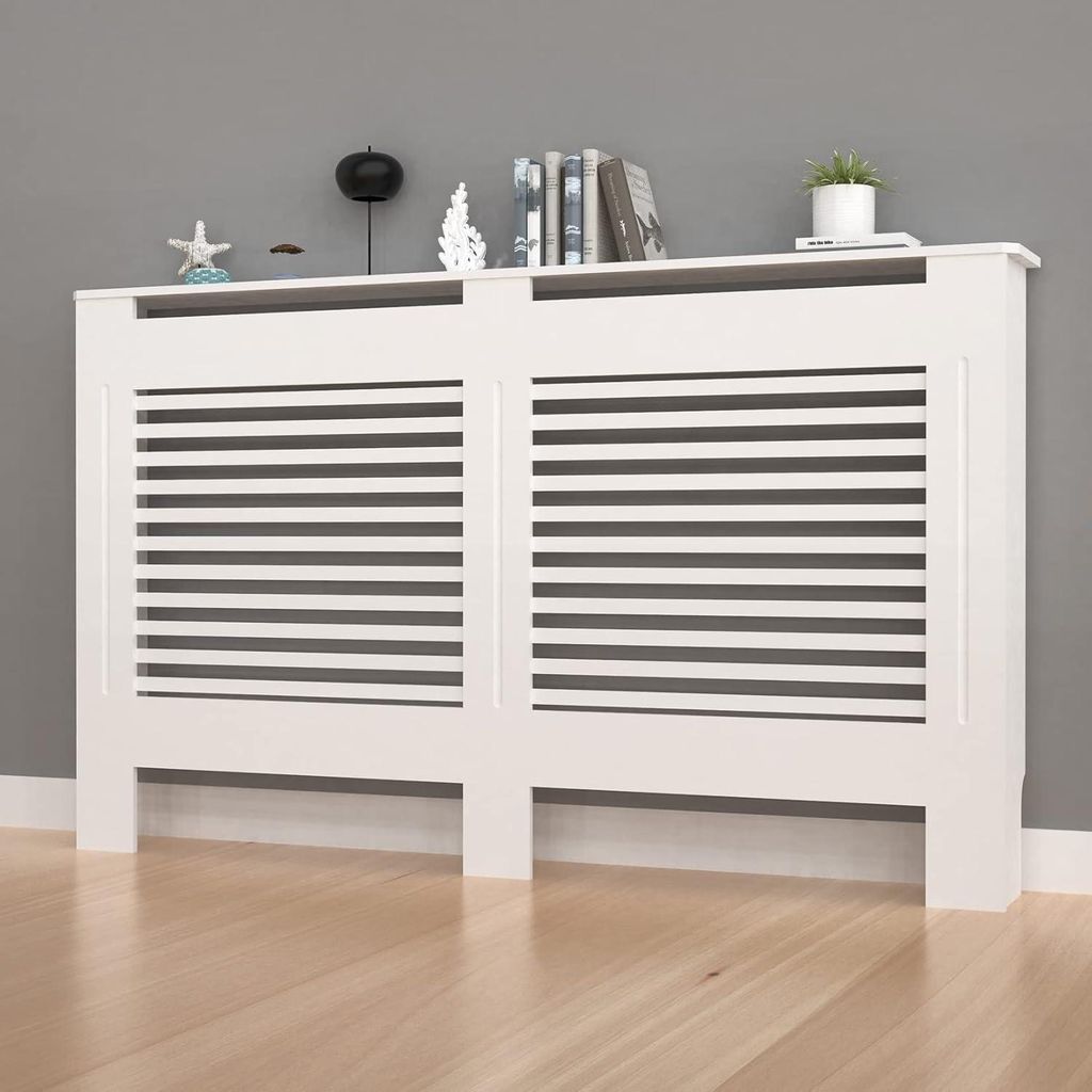A white radiator cover with horizontal slats is shown against a gray wall and a wooden floor. Decorative items are placed on top of the cover.