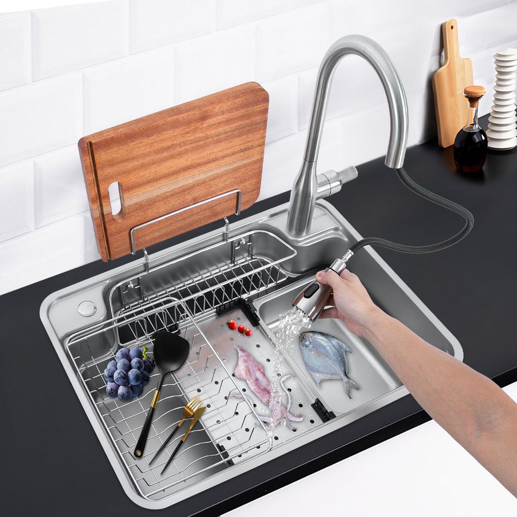 A person is using a pull-out faucet to rinse food in a kitchen sink.