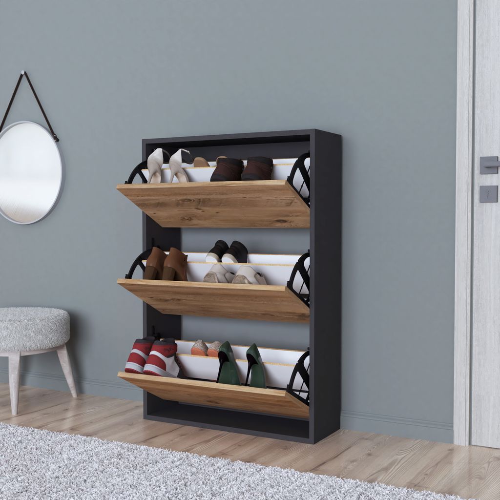 A shoe cabinet with three flip-down drawers filled with shoes, placed in a hallway next to a stool and a mirror.