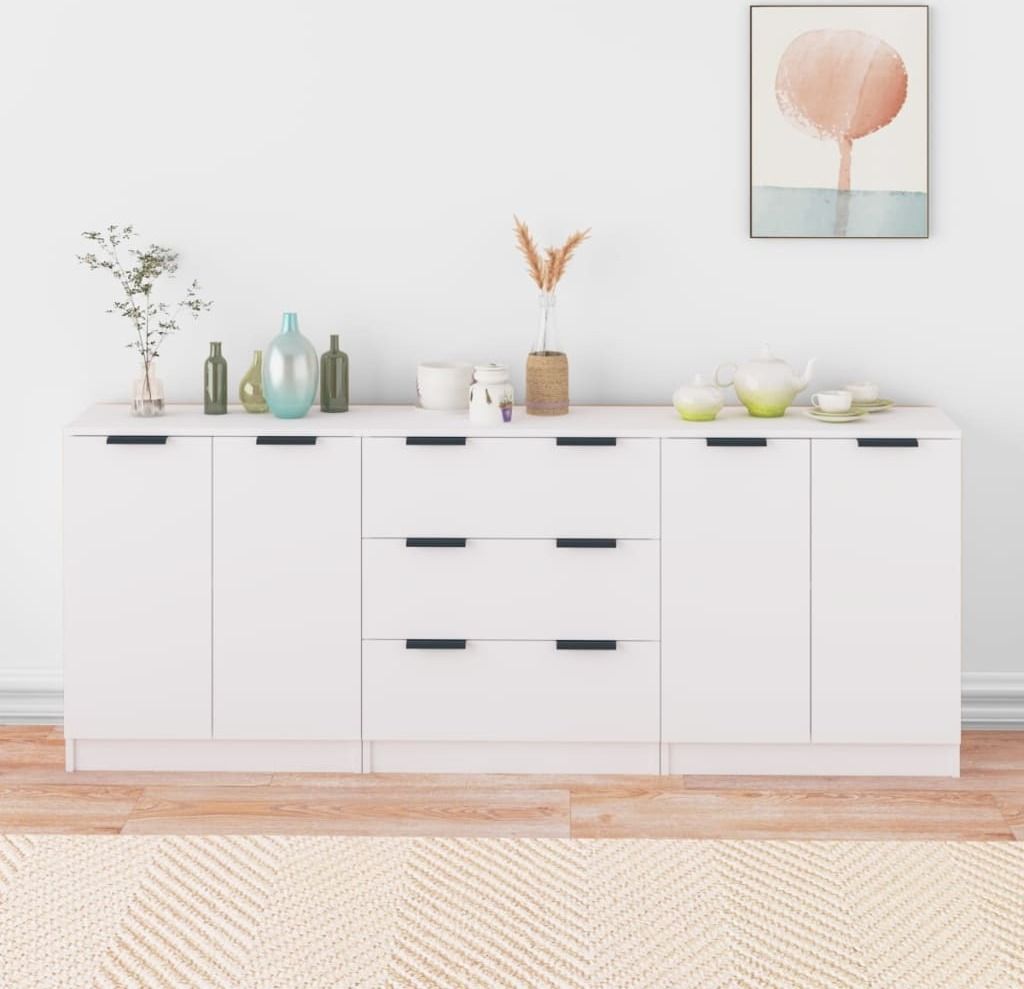 A white sideboard with various decorative items on top, against a white wall.