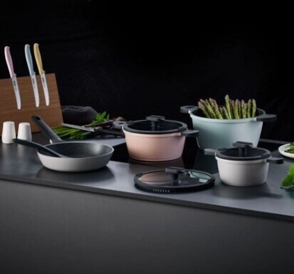 A collection of cookware and kitchen utensils displayed on a dark countertop.