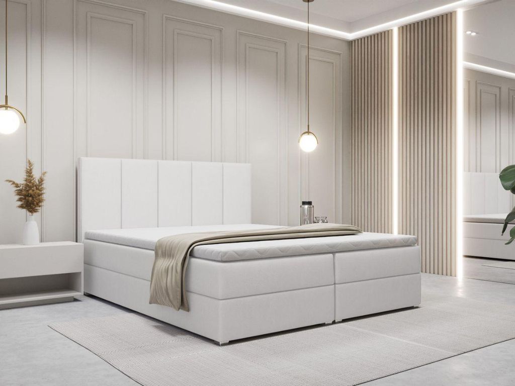 A white boxspring bed with a headboard and a beige throw blanket is shown in a modern bedroom setting.
