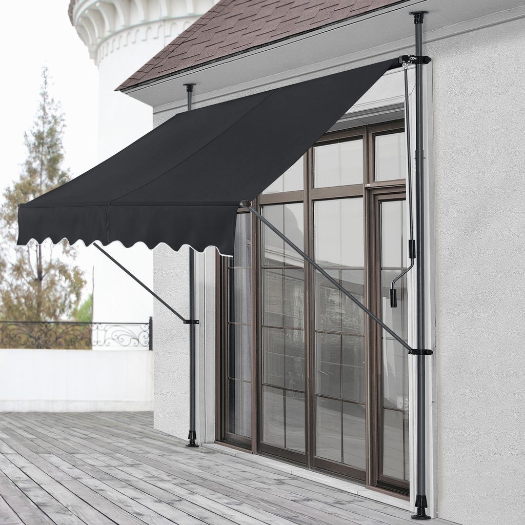 A black awning is extended over a wooden deck in front of a large window.