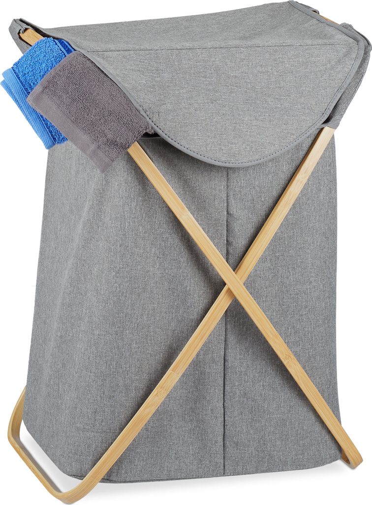 A grey fabric laundry basket with wooden cross supports, holding two folded towels.