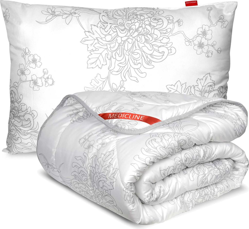 A white pillow and a folded white comforter with a gray floral pattern are displayed against a white background.