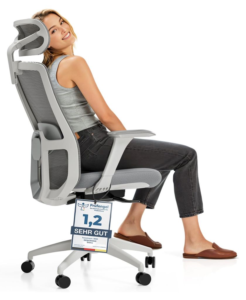 A woman is sitting in an ergonomic office chair, smiling at the camera. A certification tag is hanging from the chair.