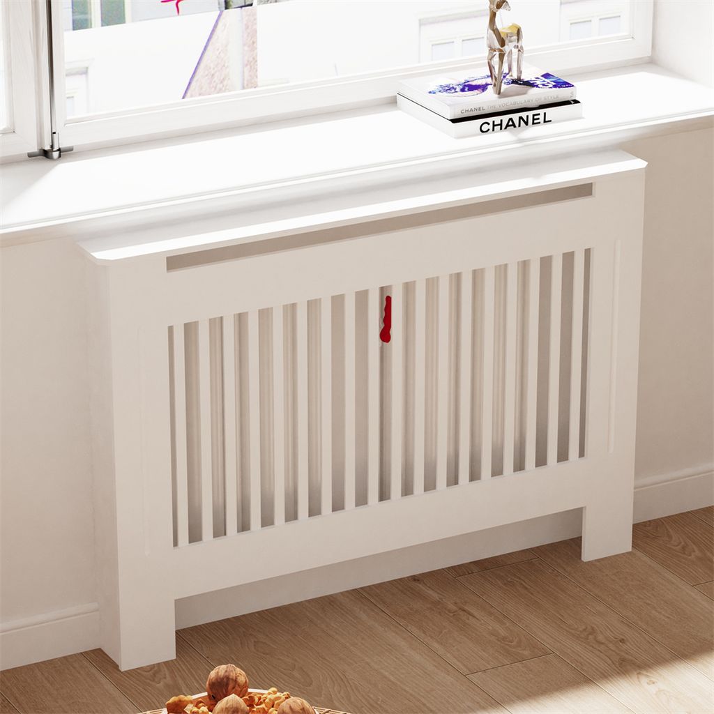 A white radiator cover with vertical slats and a shelf on top, placed in front of a window.