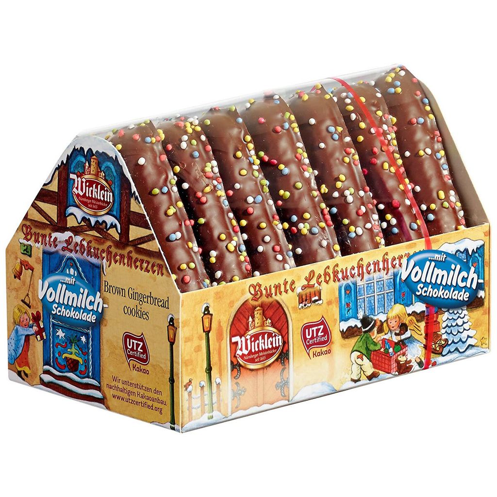 A box of chocolate-covered gingerbread cookies shaped like houses, decorated with colorful sprinkles.