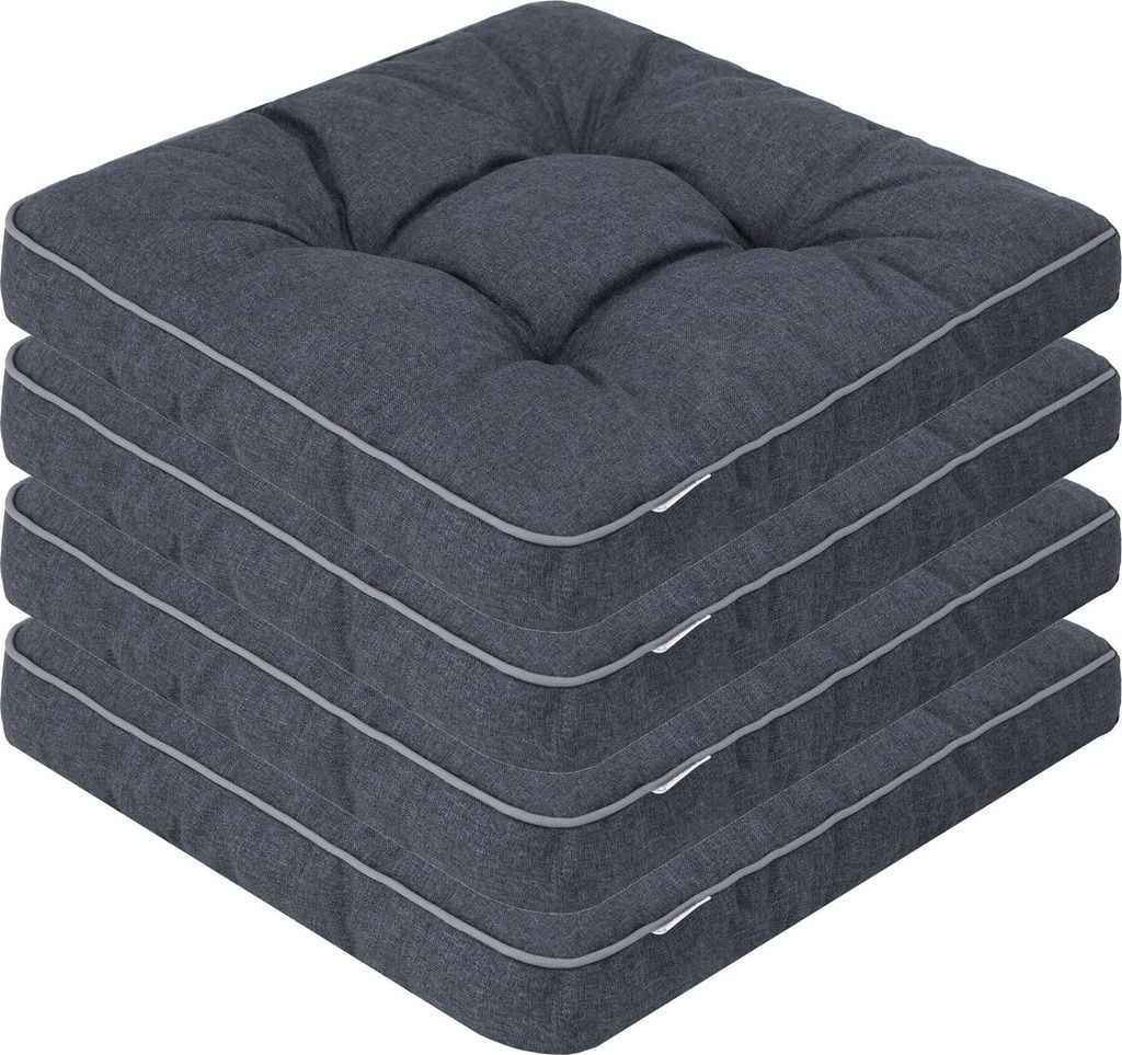 A stack of four dark gray seat cushions with light gray piping.
