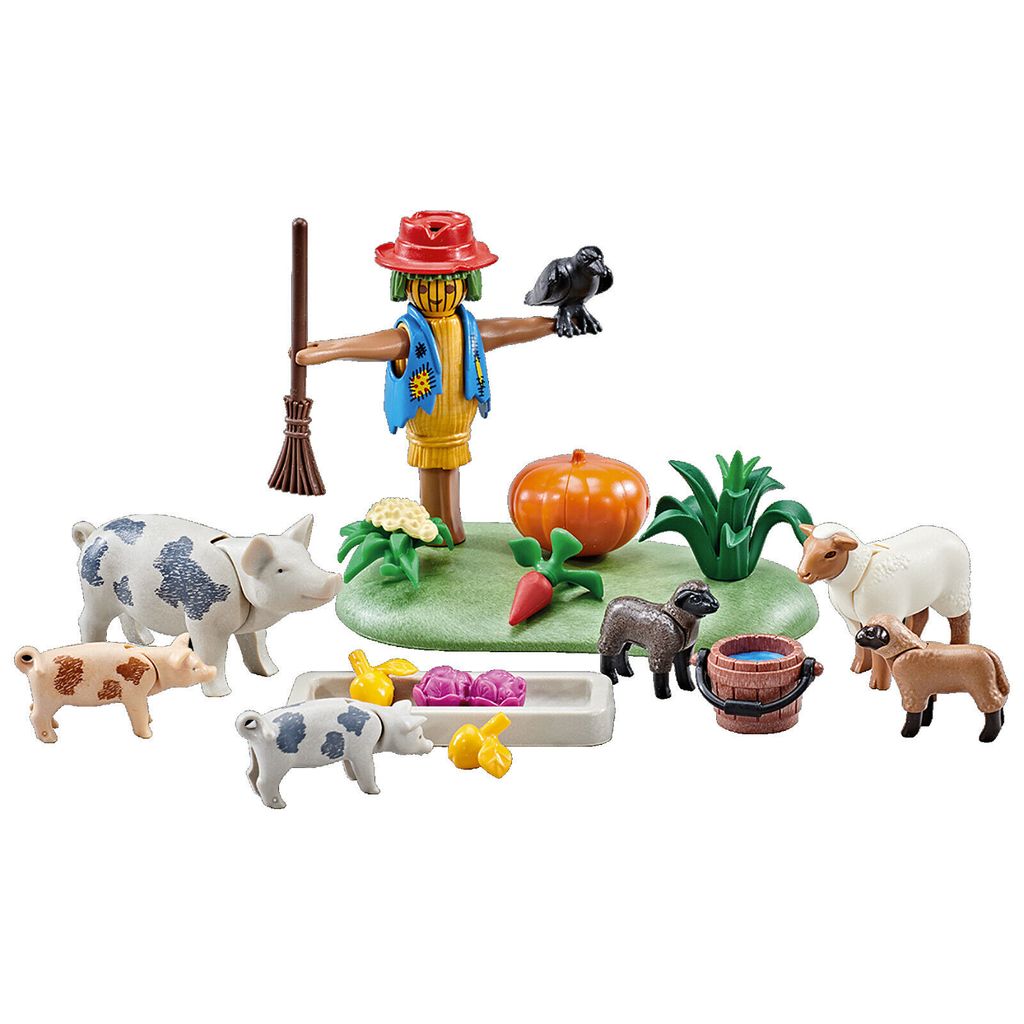 A collection of farm-themed toy figures including a scarecrow, pigs, sheep, a pumpkin, and other accessories, arranged on a green base.