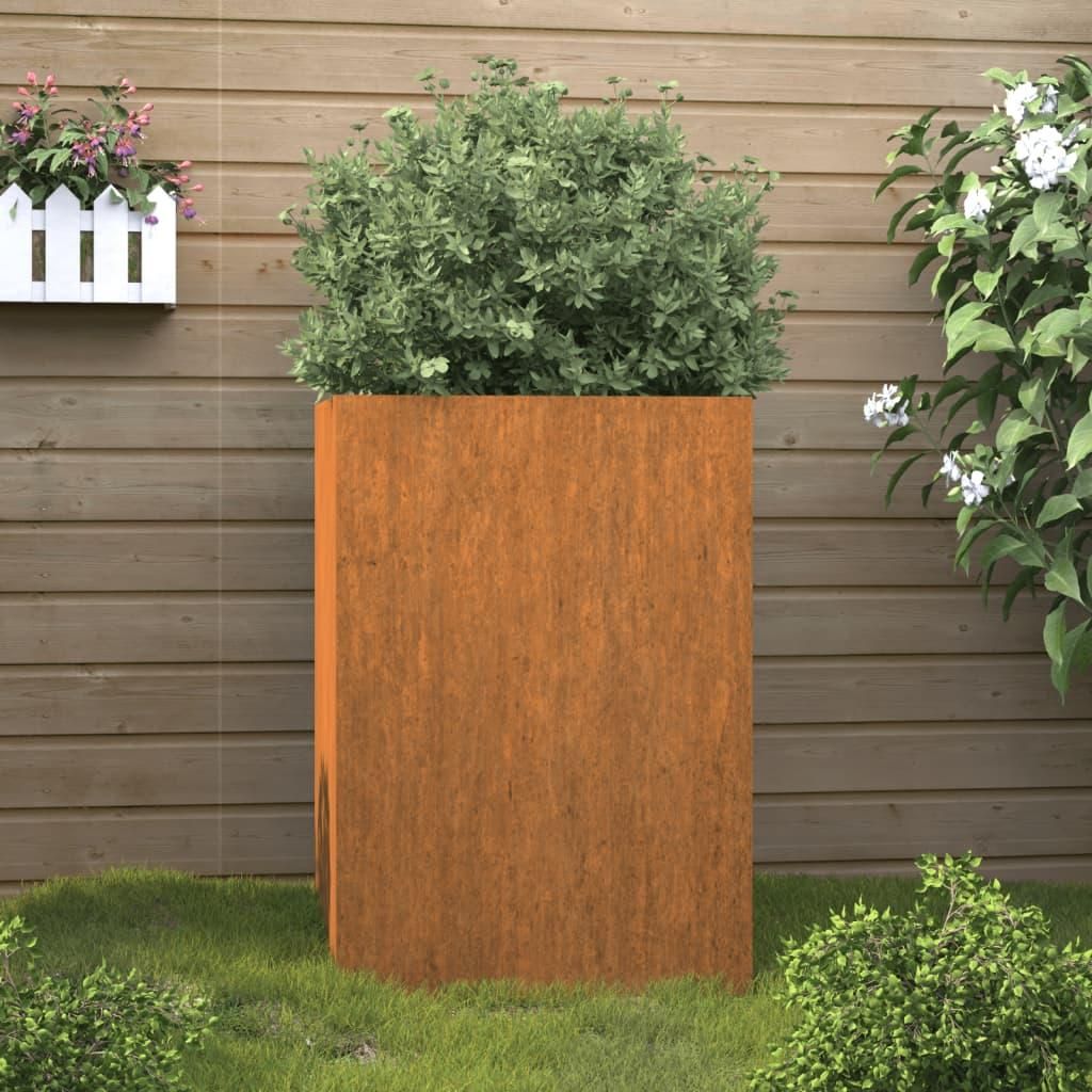A tall, rectangular corten steel planter with a green bush inside, placed on a lawn in front of a wooden fence.