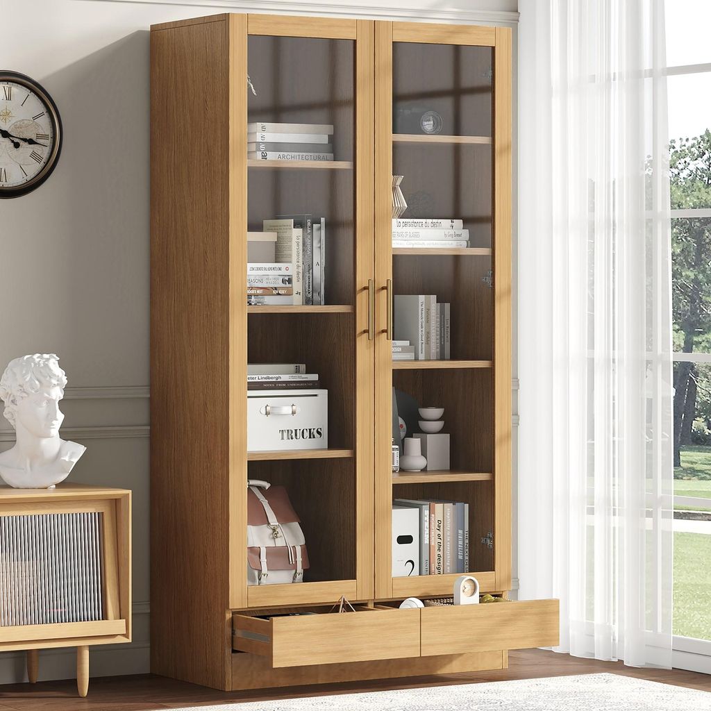A wooden display cabinet with glass doors and drawers, filled with books and decorative items, placed in a room with a clock and a bust on a side table.