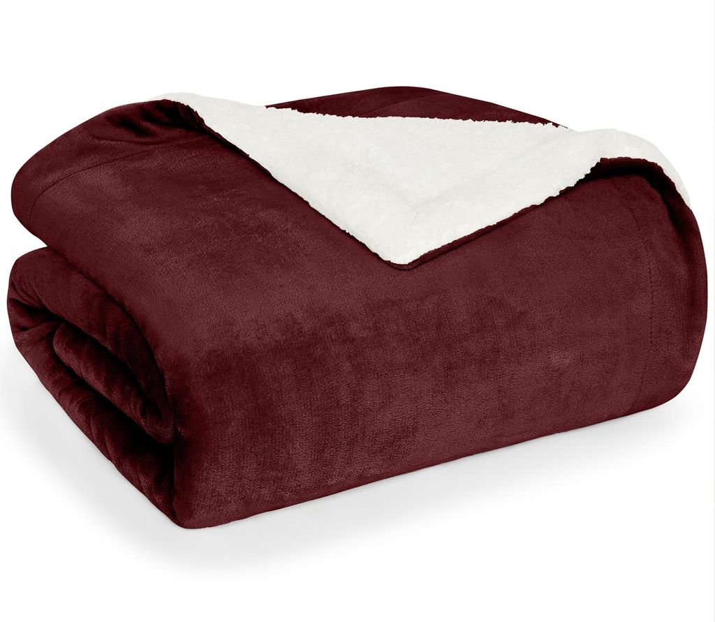 A folded dark red blanket with a white sherpa lining is shown against a white background.