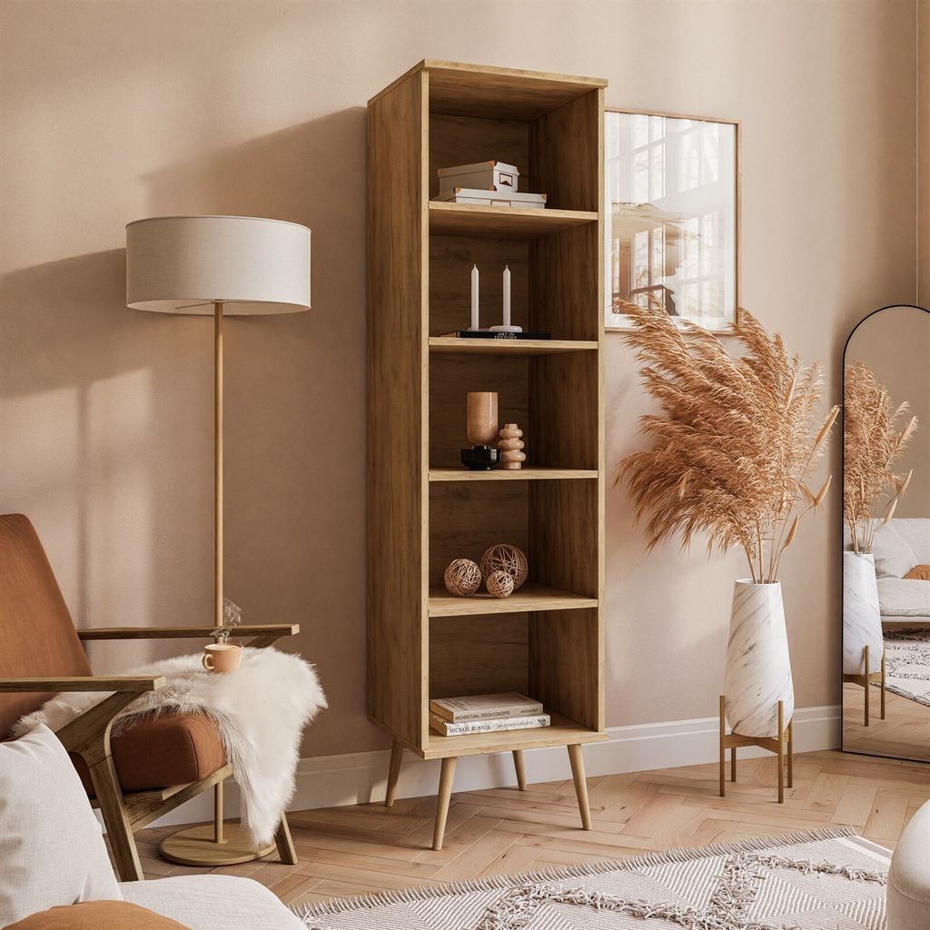 A tall wooden bookshelf filled with decorative items, placed in a living room setting next to a chair and a floor lamp.