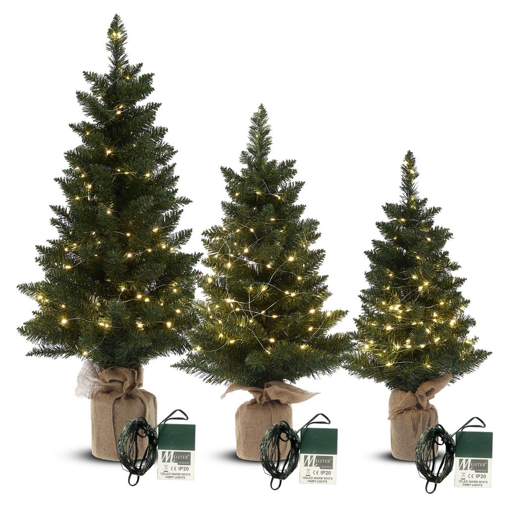 Three artificial Christmas trees of varying heights, each wrapped in burlap at the base and adorned with LED lights.