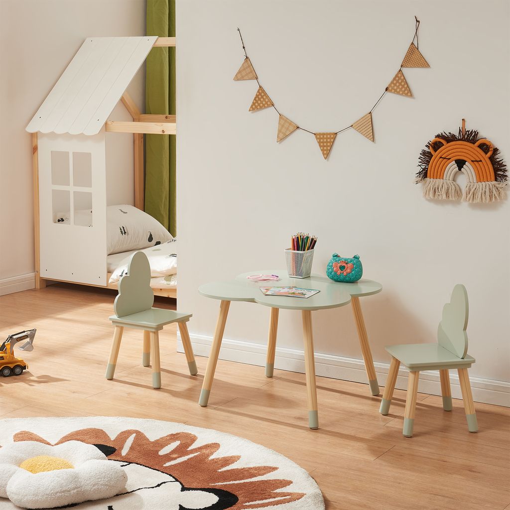 A child's bedroom with a bed, a table and chairs set, and decorative items on the wall.