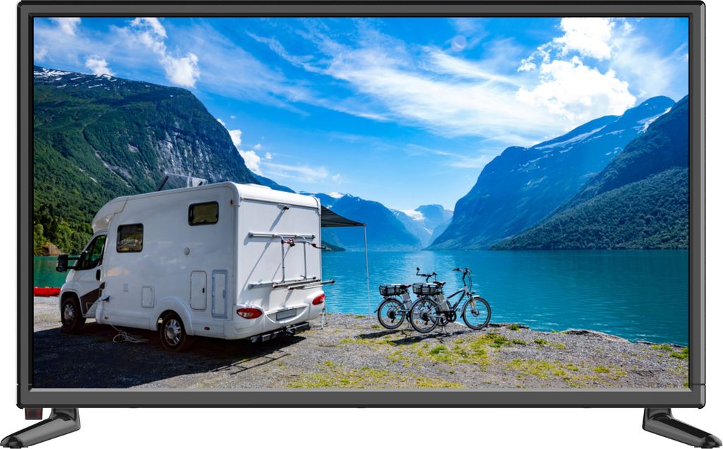 A motorhome parked by a lake with mountains in the background and two bicycles in the foreground.
