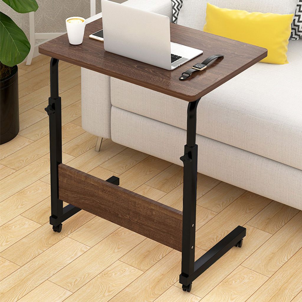 A small wooden table with a laptop and a cup on it, placed next to a sofa.