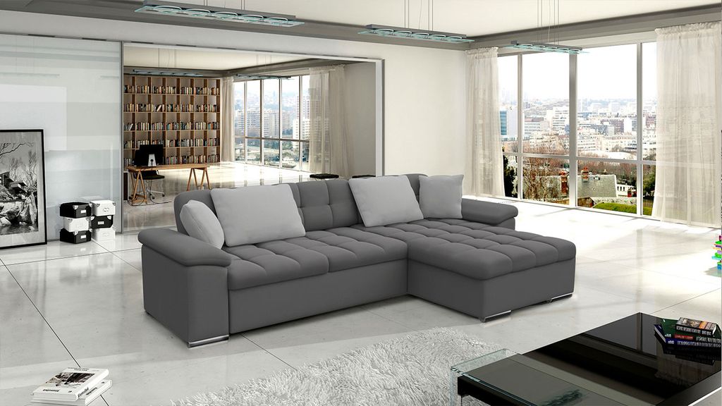 A modern living room with a large sectional sofa, a coffee table, and large windows overlooking a city.