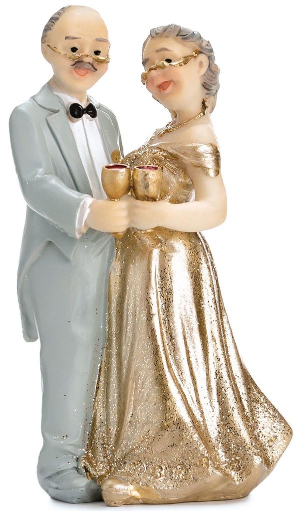 Figur eines älteren Ehepaares als Tortenaufsatz zur goldenen Hochzeit, Mann im hellen Anzug und Frau im goldenen Kleid stoßen mit Sektgläsern an.