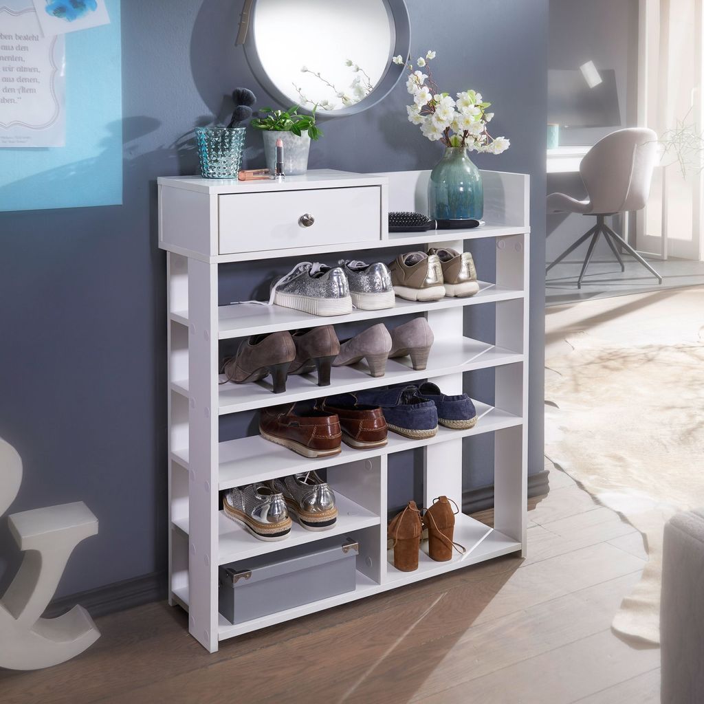 A white shoe rack filled with various shoes, placed in a room with a blue wall and a mirror.
