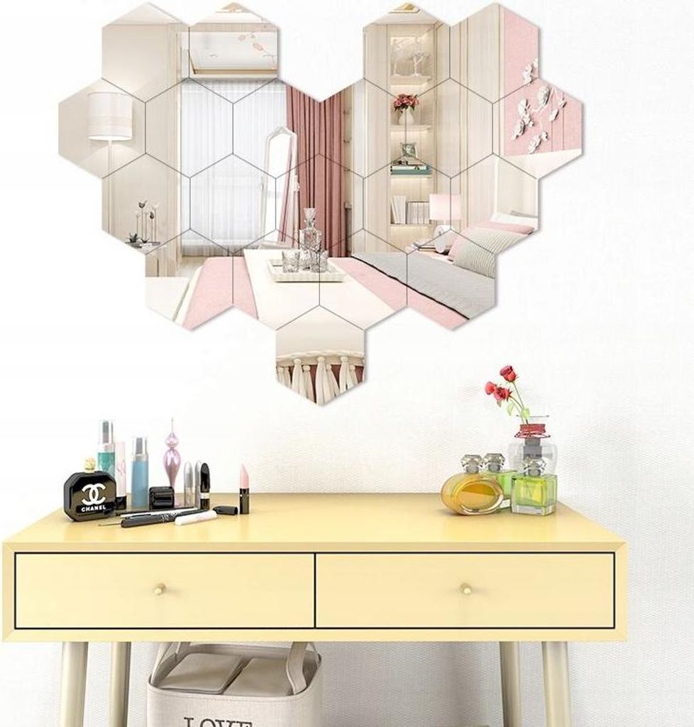 A vanity table with makeup and perfume, with a hexagonal mirror arrangement on the wall above it.