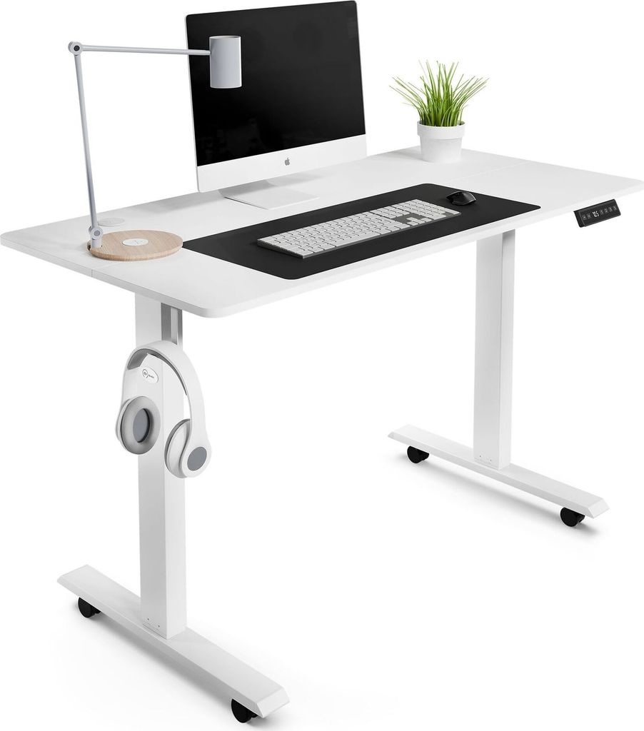 A white adjustable standing desk with a computer, keyboard, mouse, lamp, and headphones.