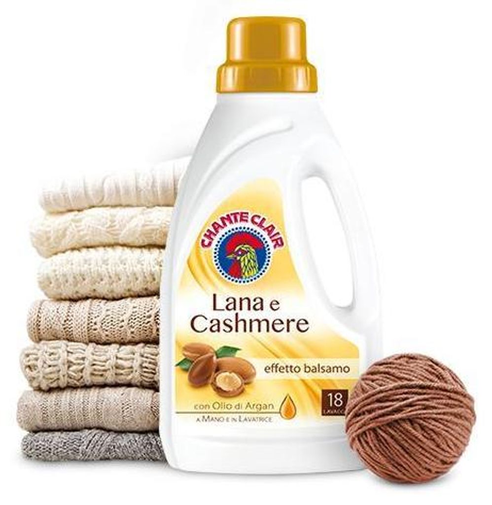 A bottle of Chante Clair laundry detergent for wool and cashmere, next to a stack of folded sweaters and a ball of yarn.