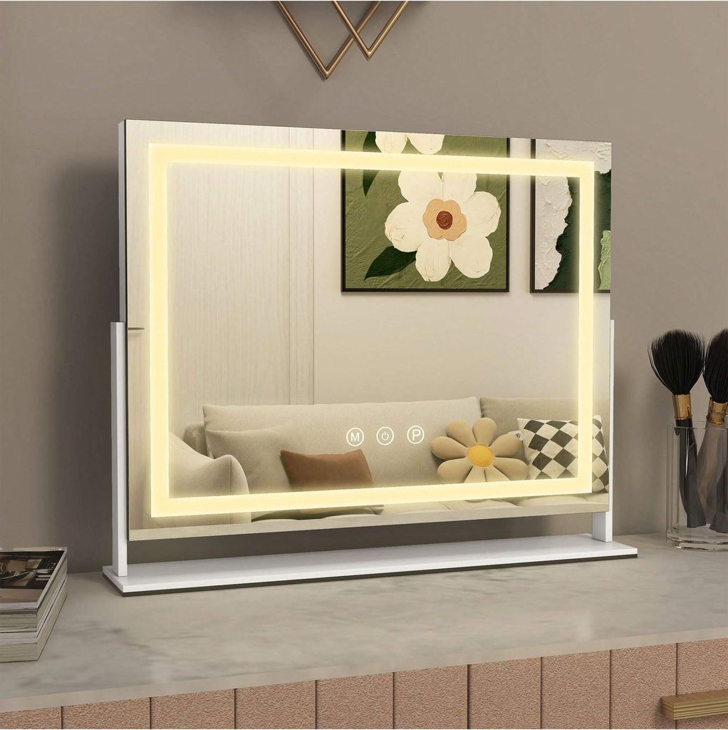 A lighted makeup mirror on a vanity table, with artwork and makeup brushes in the background.