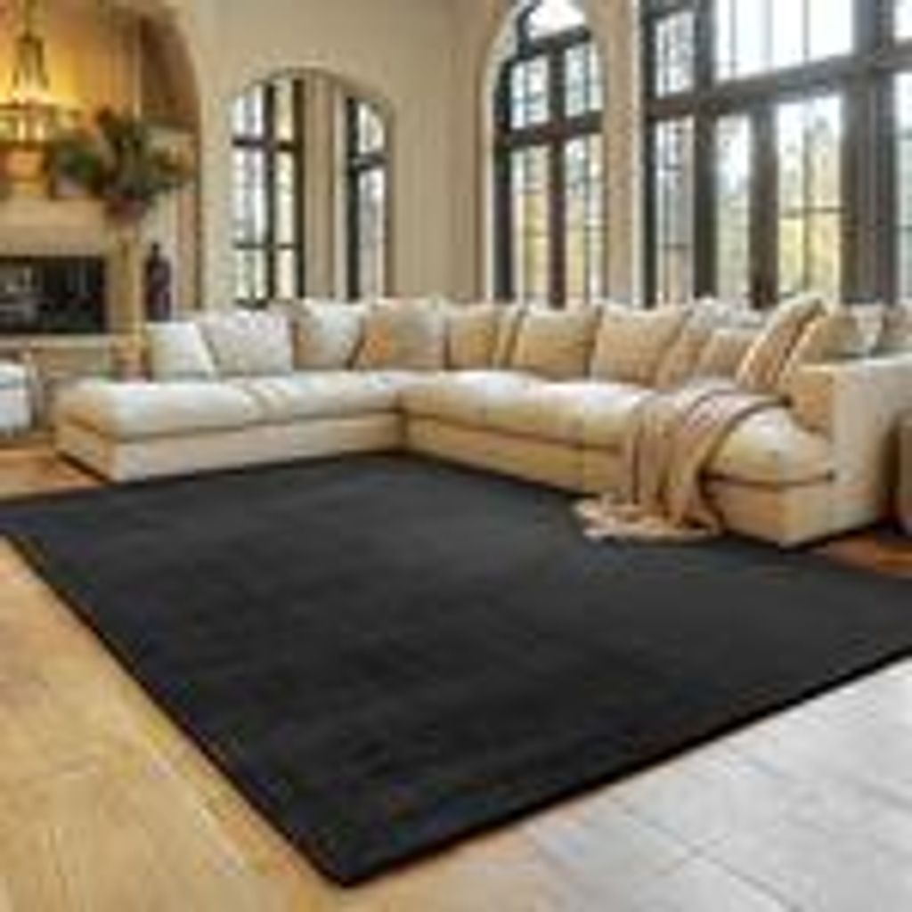 A living room with a large sectional sofa and a black rug.