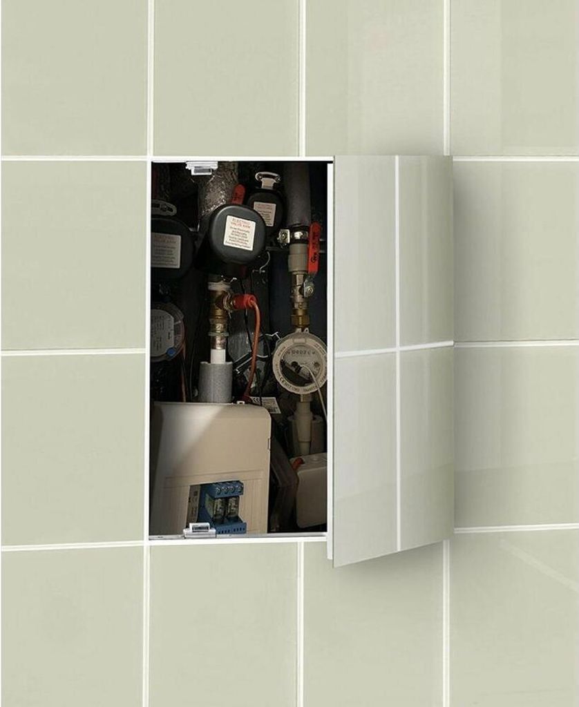 A close-up view of a plumbing inspection door, showing various pipes, meters, and valves.