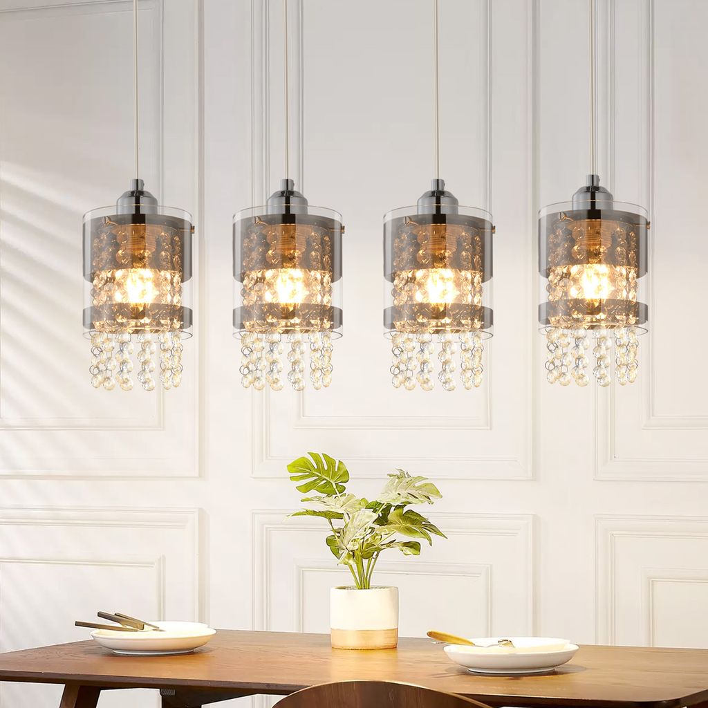 Four pendant lights hanging above a dining table with a plant and place settings.