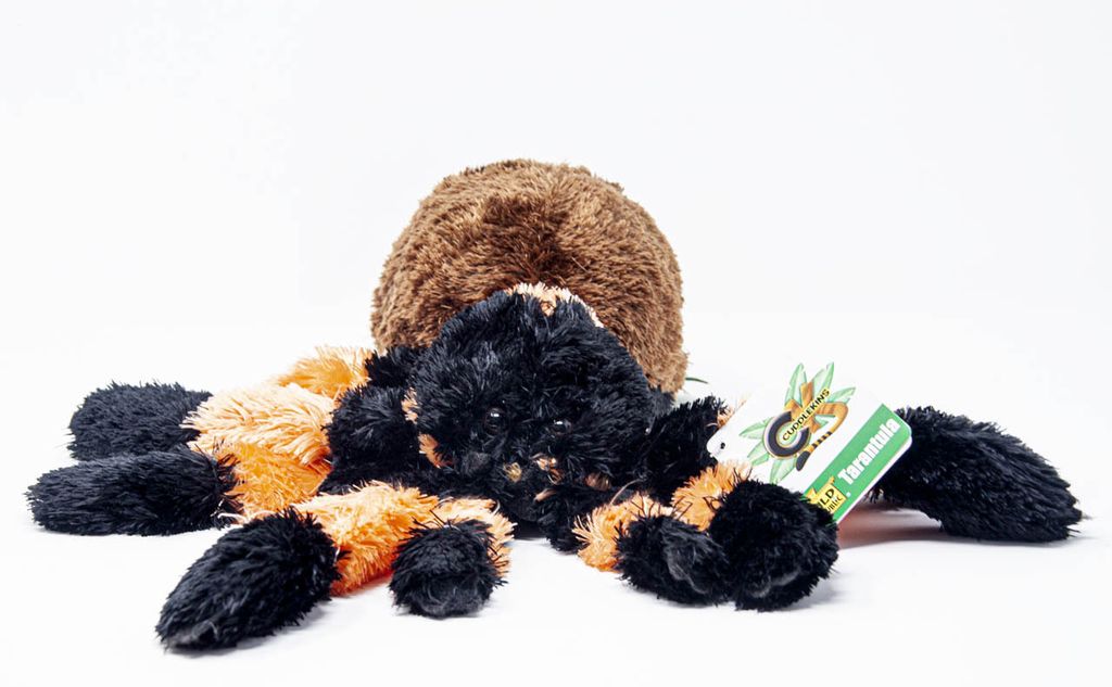 A plush toy tarantula is lying on a white background.