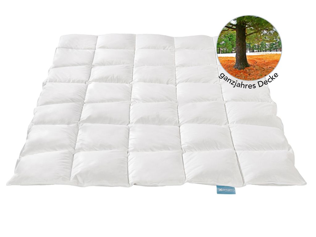 A white quilted comforter is laid out flat on a white background. A circular inset image shows a tree in an autumn landscape.